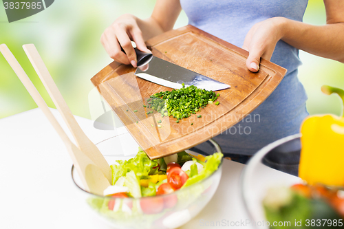 Image of close up of woman with chopped onion cooking salad