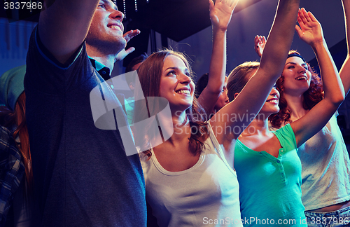 Image of smiling friends at concert in club