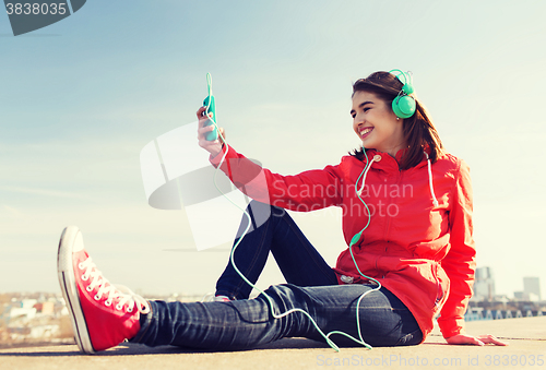 Image of happy young woman with smartphone and headphones