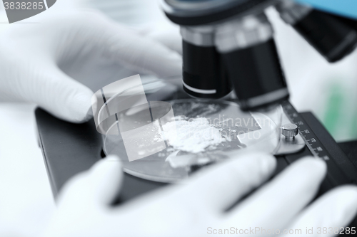 Image of close up of hand with microscope and powder sample