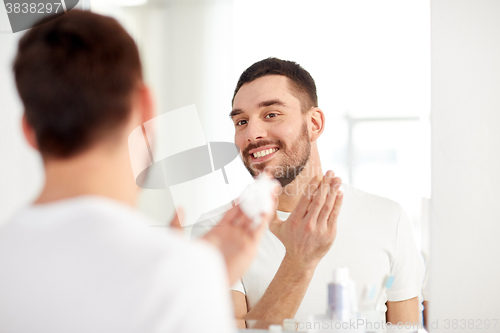 Image of happy man applying shaving foam at bathroom mirror