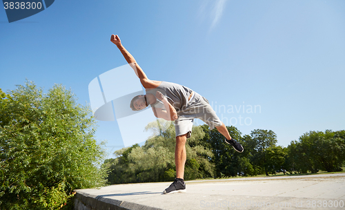 Image of sporty young man jumping in summer park