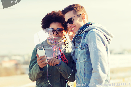 Image of smiling couple with smartphone and earphones