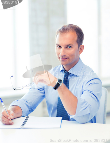 Image of businessman with spectacles writing in notebook