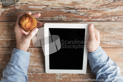 Image of close up of male hands with tablet pc and muffin