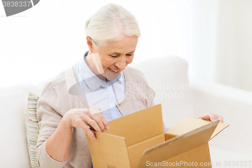 Image of happy senior woman with parcel box at home