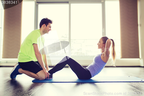 Image of woman with personal trainer doing sit ups in gym