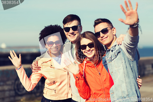 Image of happy teenage friends in shades waving hands