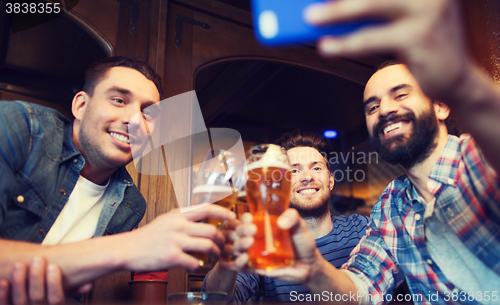 Image of male friends with smartphone drinking beer at bar