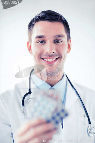 Image of young male doctor with packs of pills