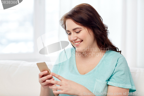 Image of happy plus size woman with smartphone at home