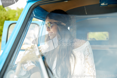 Image of smiling young hippie woman in minivan car