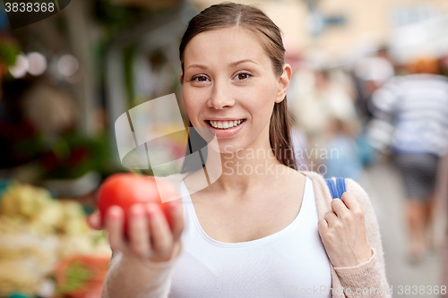 Image of happy woman holding tomato at street market