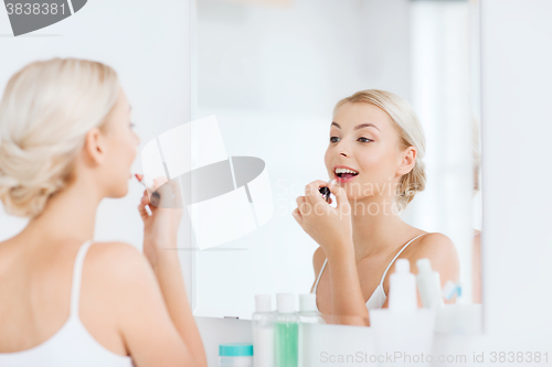 Image of woman with lipstick applying make up at bathroom