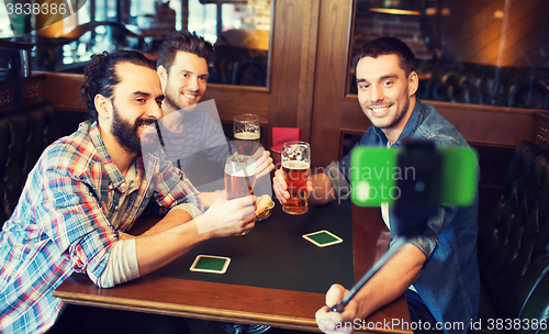 Image of friends taking selfie and drinking beer at bar