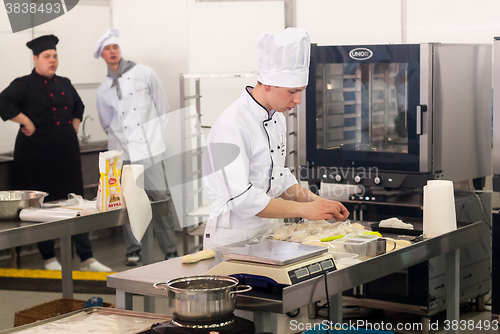 Image of Young cook prepares food in competition