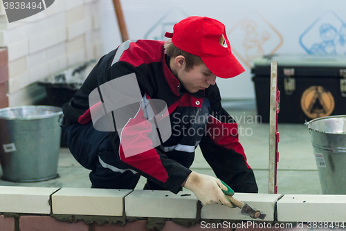 Image of Young bricklayer performs a task of competition