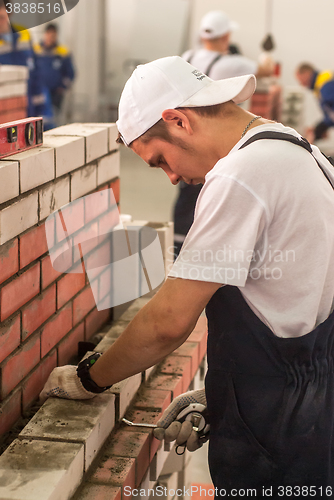 Image of Young bricklayer performs a task of competition