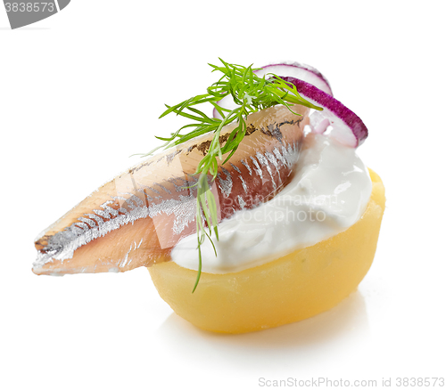 Image of boiled potato decorated with anchovy, sour cream, dill and onion