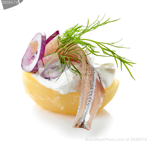 Image of boiled potato decorated with anchovy, sour cream, dill and onion