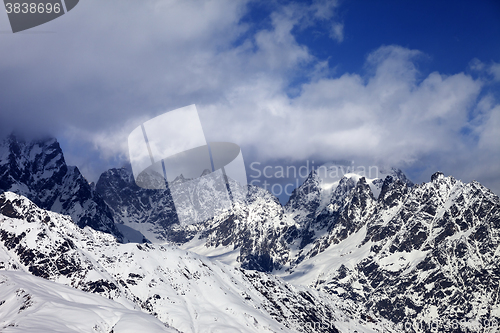 Image of Snowy rocks in clouds at sunny day