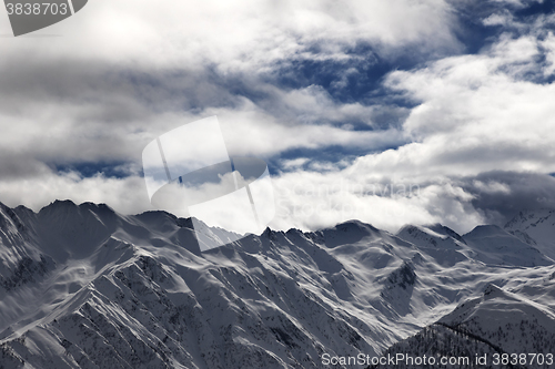 Image of Ssnowy mountains and cloudy sky at evening