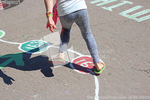 Image of girl runs on the childish drawings on the asphalt