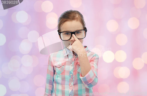 Image of happy little girl in eyeglasses over pink lights