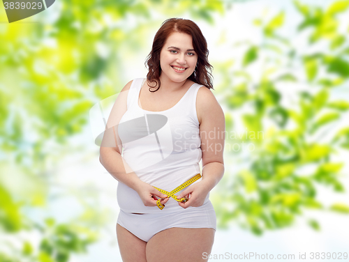 Image of happy young plus size woman with measuring tape