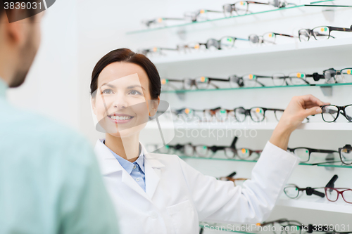 Image of optician showing glasses to man at optics store