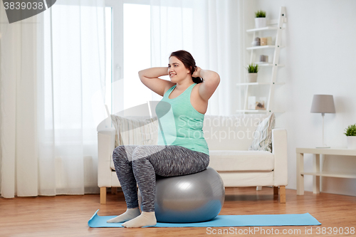 Image of plus size woman exercising with fitness ball