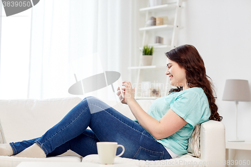 Image of happy plus size woman with smartphone at home