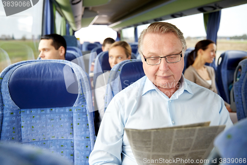Image of happy senior man reading newspaper in travel bus