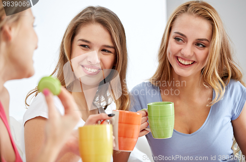 Image of happy young women drinking tea with sweets at home