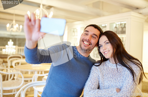 Image of couple taking smartphone selfie at cafe restaurant