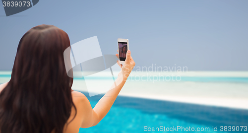 Image of young woman taking selfie with smartphone