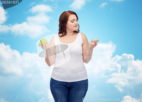 Image of young plus size woman choosing apple or cookie