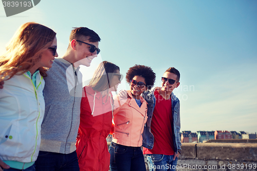 Image of happy teenage friends walking along city street