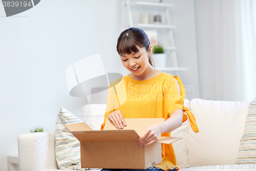 Image of happy asian young woman with parcel box at home