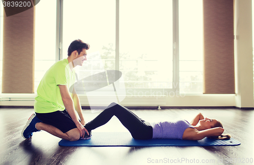 Image of woman with personal trainer doing sit ups in gym