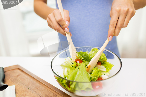 Image of close up of woman cooking vegetable salad at home