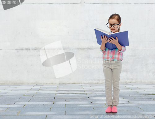 Image of happy little girl in eyeglasses reading book