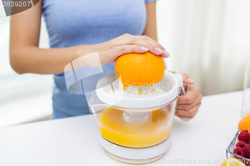 Image of close up of woman squeezing orange juice at home