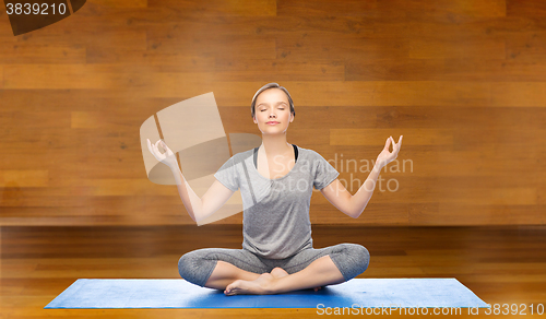 Image of woman making yoga meditation in lotus pose on mat