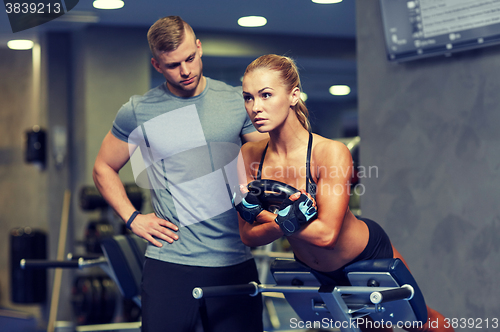 Image of woman with personal trainer flexing muscles in gym