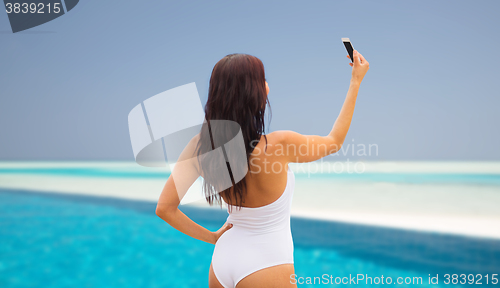 Image of young woman taking selfie with smartphone