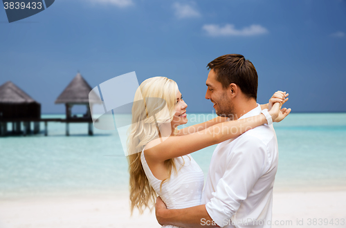 Image of happy couple having fun over beach with bungalow