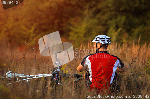 Image of Young cute lady posing on a bike near the wall