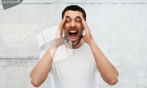 Image of crazy shouting man in t-shirt over gray wall