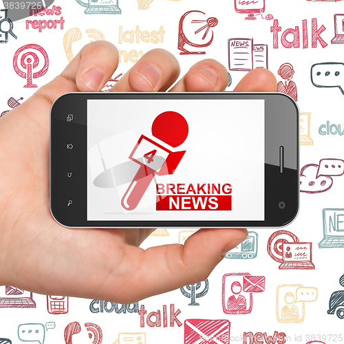 Image of News concept: Hand Holding Smartphone with Breaking News And Microphone on display